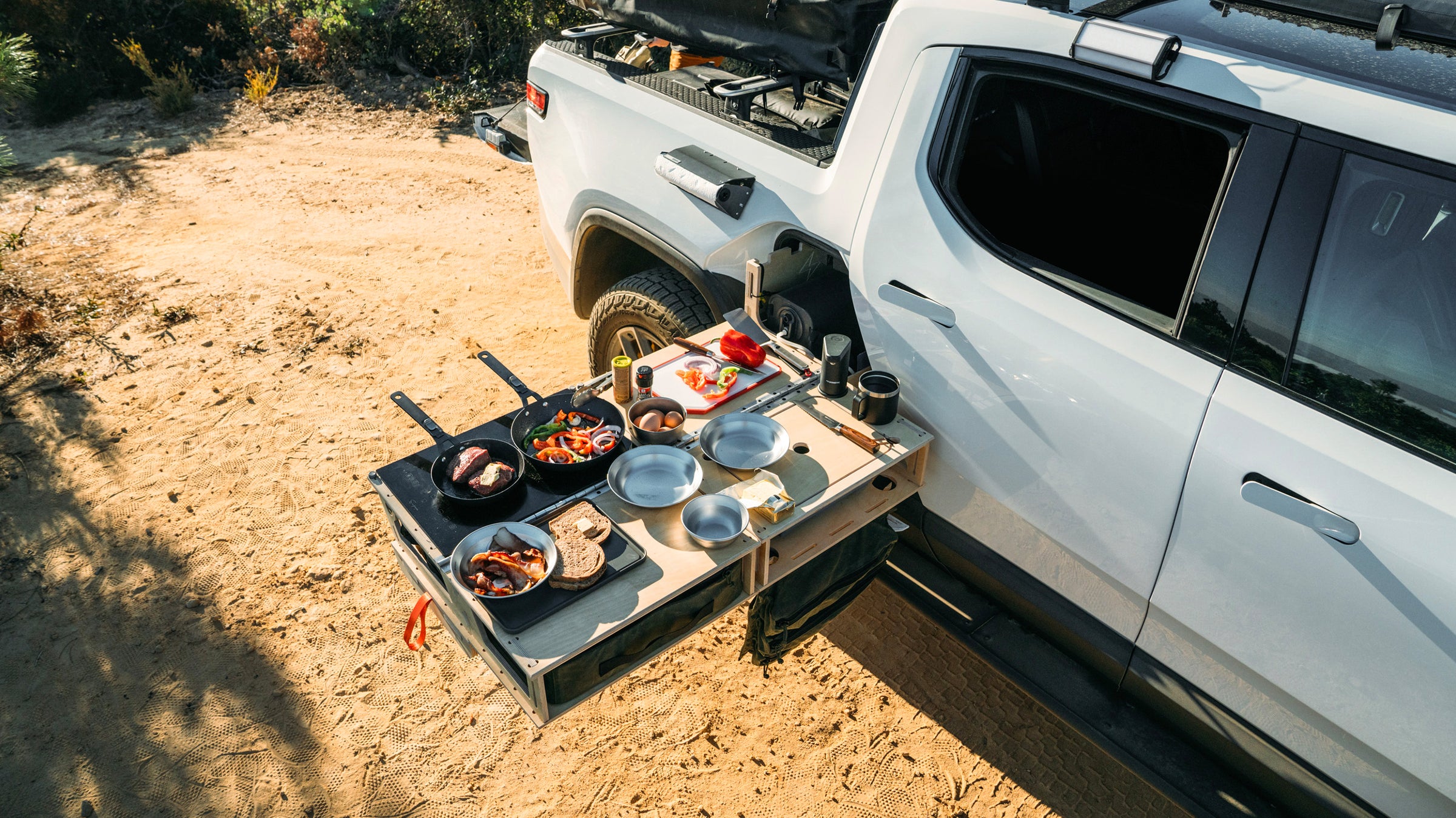 Rivian R1T with a Thunderbolt Camp Kitchen cooking food in the wild. 